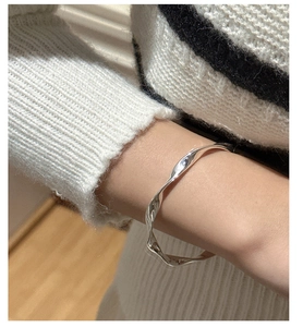Close-up of S925 sterling silver twisted wave bracelet on wrist with polished finish