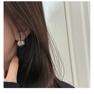 Detailed close-up of a sterling silver spherical earring featuring a laser-cut texture