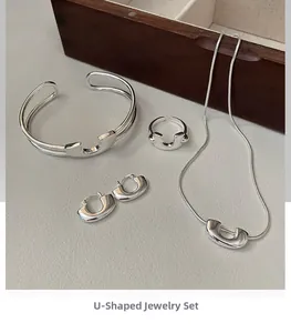 Dettaglio ravvicinato di un set di gioielli minimalisti in argento a forma di U su legno