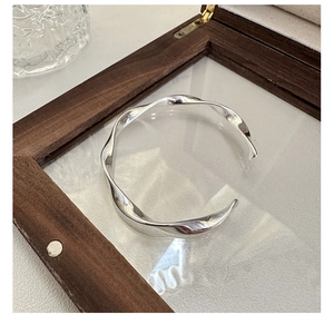 Detailed view of silver S925 twisted wavy cuff bracelet in a wooden display case