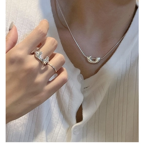 Dettaglio della collana con pendente a U d'argento e anelli spessi su modella in maglia