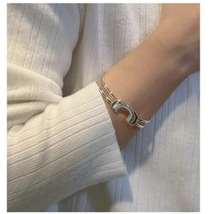 Dettaglio del bracciale aperto in argento a doppia linea con design a U sul polso