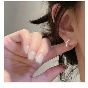 Primo piano di orecchini a cerchio minimalisti in argento S925 indossati da una modella