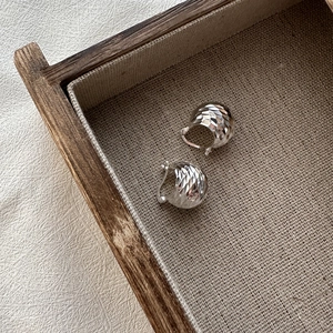 S925 sterling silver diamond-cut earrings with shimmering texture on rustic linen