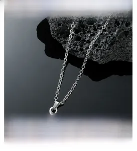 Macro shot of silver cross pendant with sparkling zircons on black volcanic stone