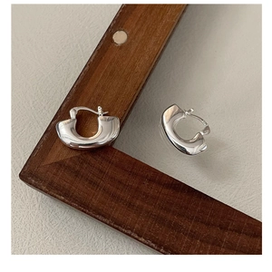 Dettaglio degli orecchini a U in argento S925 con trama in metallo liquido e marchio S925