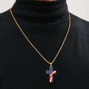 Macro shot of men's gold cross pendant with USA flag enamel on a black sweater