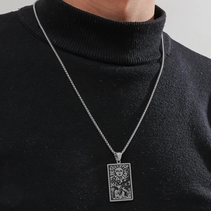 Macro shot of stainless steel Tarot The Sun pendant necklace on black fabric