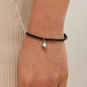 Adjustable black braided rope bracelet featuring magnetic silver heart-shaped pendant on wrist
