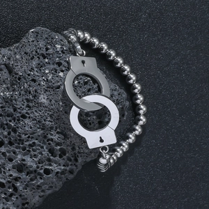Poliertes Edelstahl-Perlenarmband mit Handschellen-Anhänger auf schwarzem Lavastein