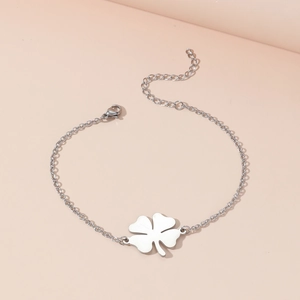 Polished stainless steel lucky clover bracelet with adjustable chain on a pink background
