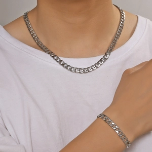 Detail van zilveren Cubaanse schakelketting en armband set gedragen door model