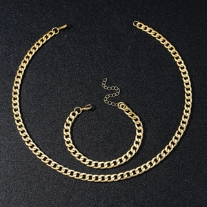 Gepolijste gouden Cubaanse schakelketting en armband set op zwarte achtergrond