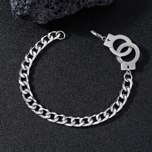Detailed view of silver handcuff pendant on polished stainless steel cuban chain bracelet