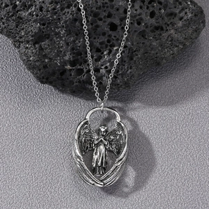 Detailed relief of a vintage angel wing pendant on a dark textured background