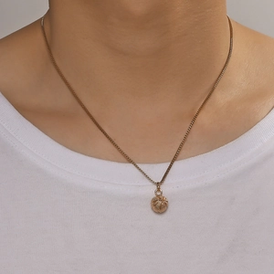 Dettaglio di una collana con ciondolo basket dorato su un modello con t-shirt bianca