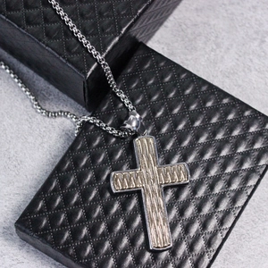 Men's two-tone cross pendant necklace with textured sword pattern on jewelry box