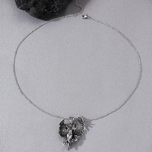 Retro silver winged goddess pendant necklace with intricate carvings on dark textured surface