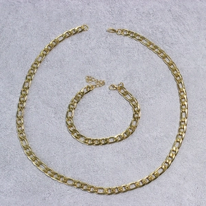 Detail of golden Figaro chain necklace and bracelet set with lobster clasp on stone surface