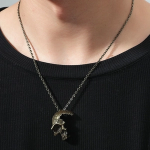 Détail d'un pendentif tête de mort gothique en bronze porté sur un pull en tricot noir