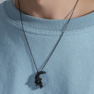 Nahaufnahme des gotischen Totenkopf-Anhängers in Schwarz auf blauem Strickpullover