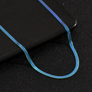 Detailed close-up of rainbow iridescent flat snake chain necklace on black surface