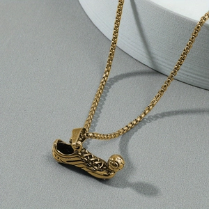 Close-up of golden football shoe pendant necklace with detailed laces on grey texture