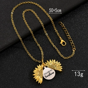 Macro detail of sunflower locket showing You Are My Sunshine engraving and chain length