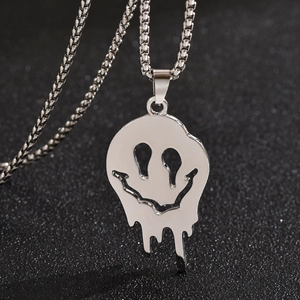 Vue macro d'un pendentif visage souriant fondu sur une chaîne en argent au fini brillant