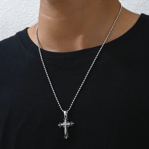 Dettaglio del ciondolo a croce argento con cristalli su una catena a palline