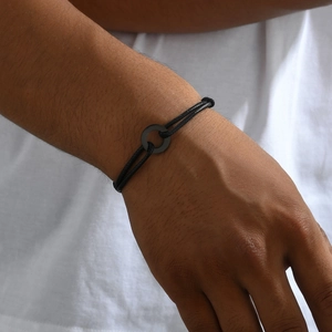 Minimalist black braided leather cord bracelet with metal ring on male wrist model