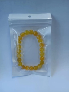 Detailed close-up of translucent yellow round beaded bracelet in simple transparent packaging