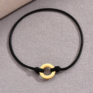Minimalist black cord bracelet with a gold stainless steel ring on a stone background