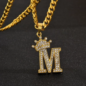 Macro shot of gold hip-hop M letter pendant with crown and iced out white crystals