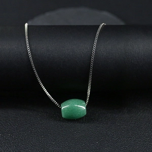 Collier avec pendentif en aventurine verte sur présentoir noir au style minimaliste