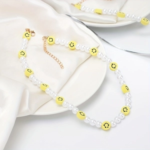 Détail du collier avec perles blanches, smileys jaunes et fermoir mousqueton doré