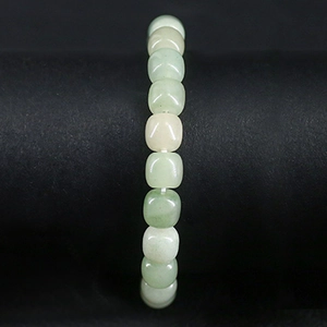 Vue macro des perles d'aventurine vert clair sur le bracelet avec une finition lisse polie