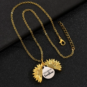 Golden sunflower locket necklace with You Are My Sunshine engraving on dark background