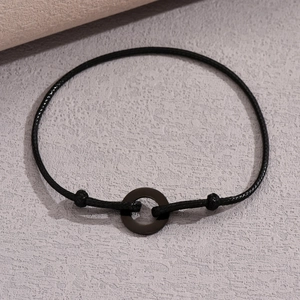Minimalist black cord bracelet with matte circular metal ring and adjustable slip knot