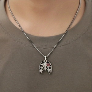 Détail macro du pendentif cage thoracique en argent avec cœur rouge sur une chaîne
