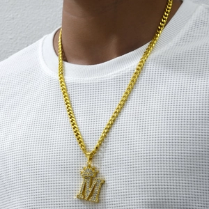 Detail of hip hop gold Cuban chain with iced-out crown M letter pendant on model