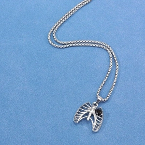 Collier gothique cage thoracique argentée avec pierre noire en cœur sur fond bleu