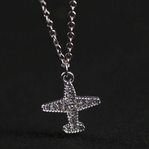 Minimalist silver airplane pendant necklace with sparkling crystals on black background