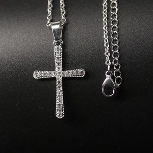 Classic silver cross necklace with pavé crystal inlay on a dark textured background