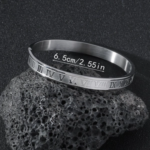 Close-up of silver stainless steel cuff with roman numerals on volcanic stone