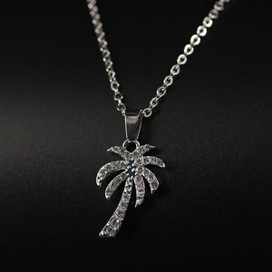 Macro shot of silver palm tree necklace pendant with sparkling cubic zirconia on black background