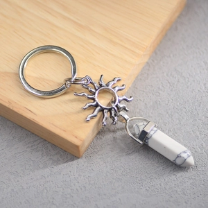 Macro shot of sun charm and white turquoise pillar on metal keychain with wood background