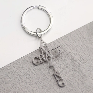 Vue macro porte-clés croix argentée avec découpe Amazing Grace sur fond en pierre