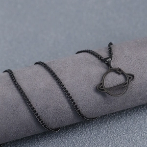 Detail of minimalist black planet pendant on a textured grey display stand