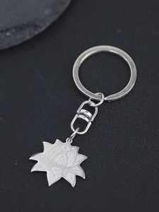 Macro detail of stainless steel lotus flower pendant on a minimalist metal keychain